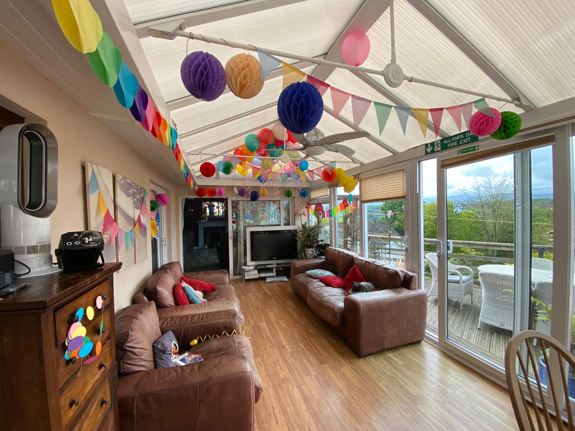 The bright conservatory at Hyland Residential Home, decorated for a celebration, with doors opening onto the garden deck
