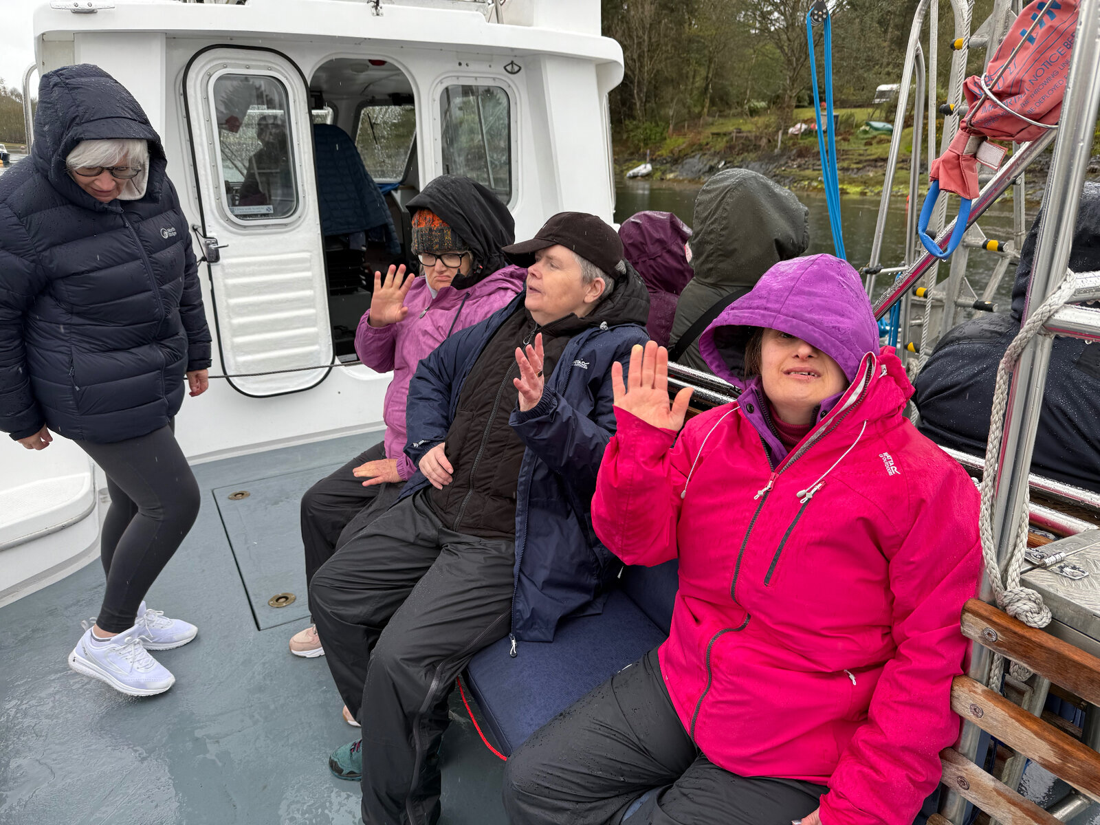 Residents waving on a boat trip in the rain