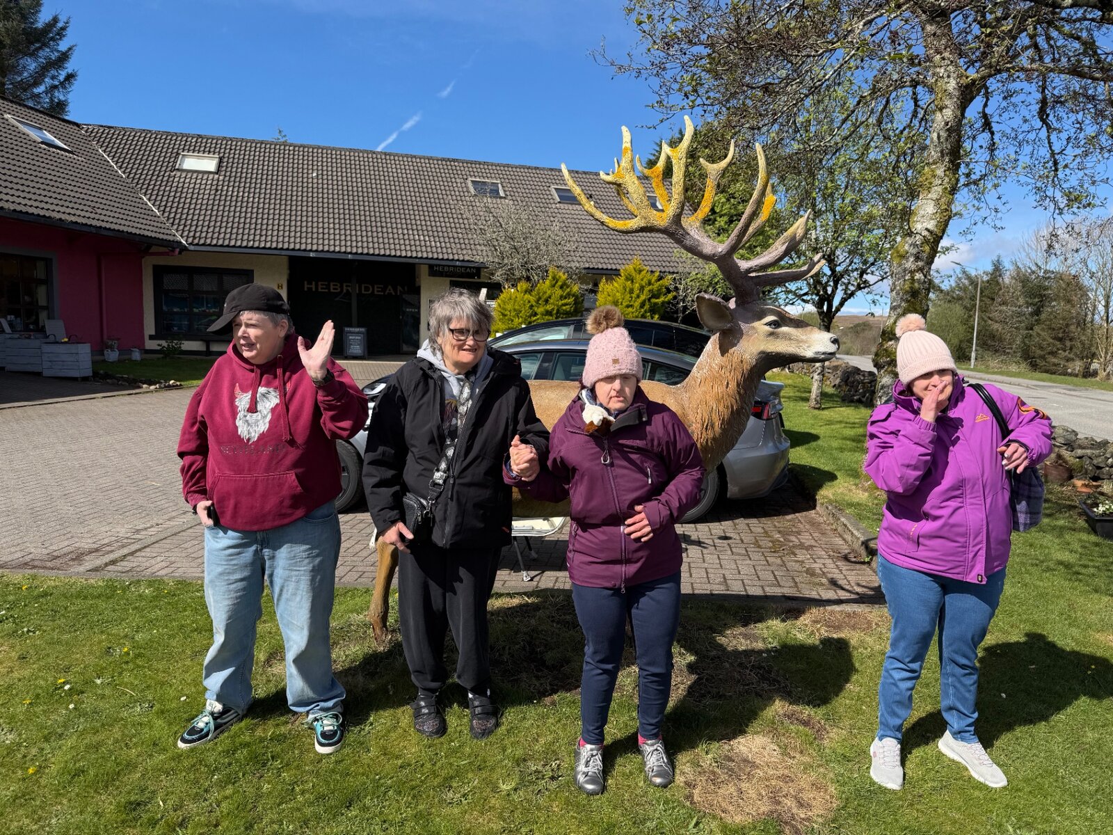 Residents standing together beside a large deer sculpture