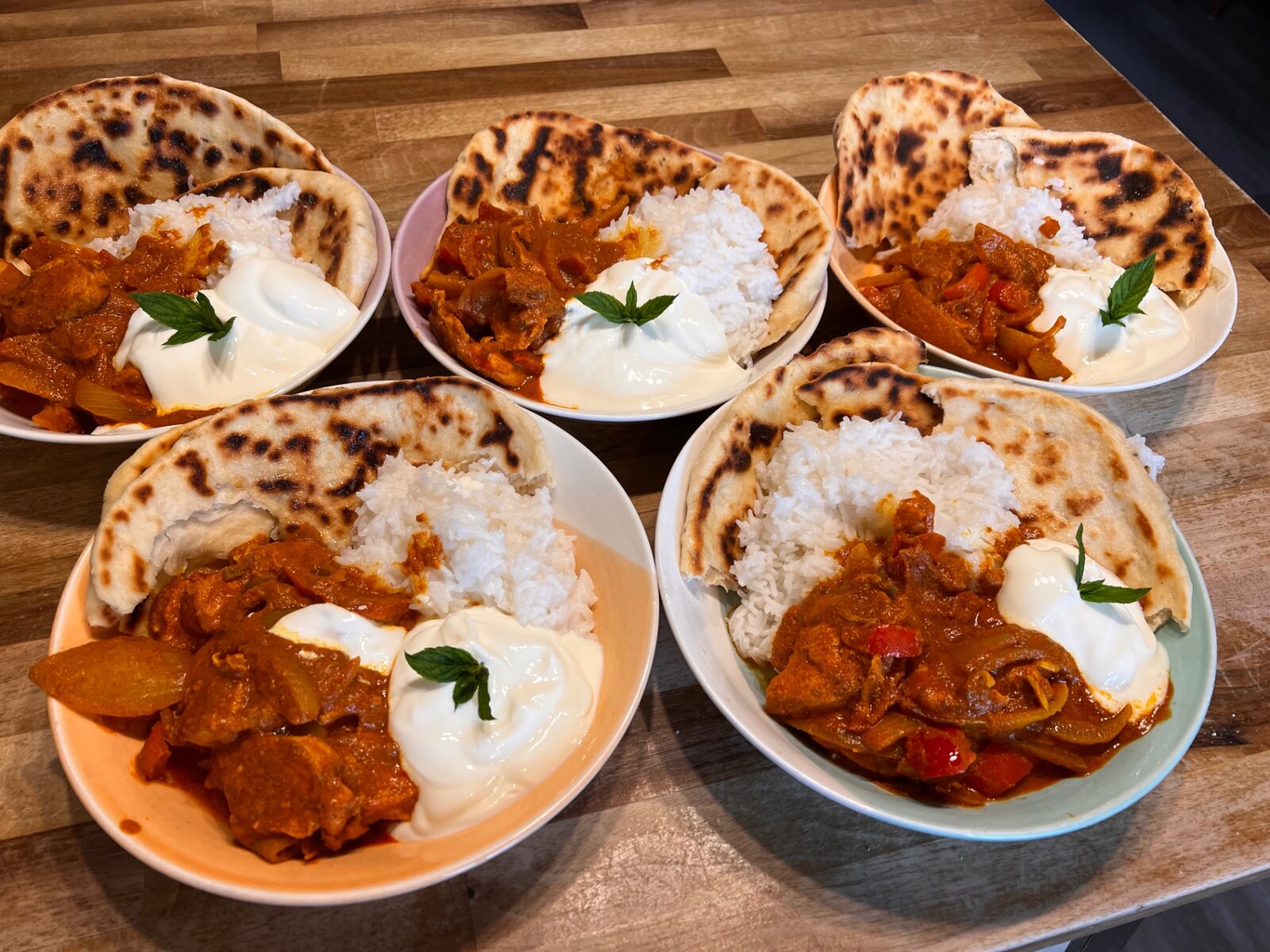 Bowls of curry with rice, naan and yoghurt